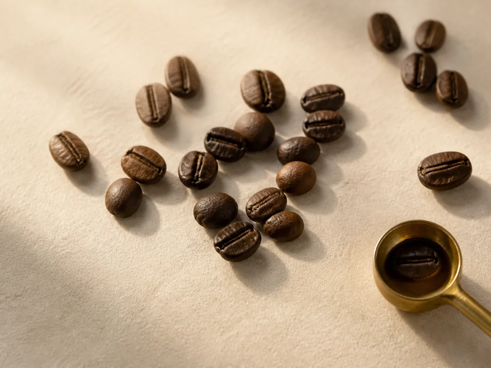 Selected roasted coffee beans on warm ivory.